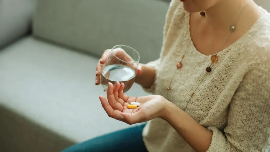 woman taking daily supplements with a glass of water