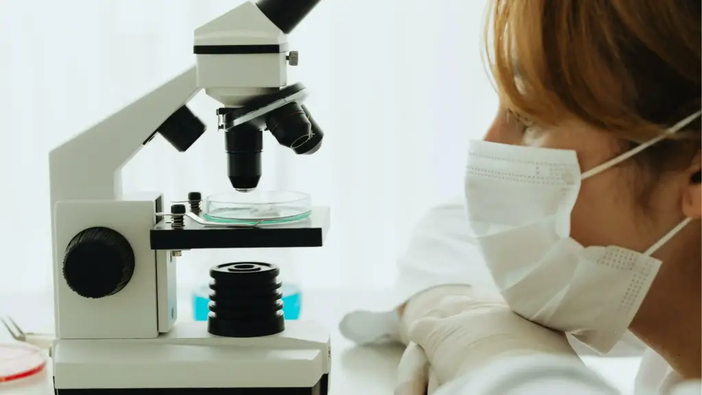 A woman observing a microscope in a laboratory setting