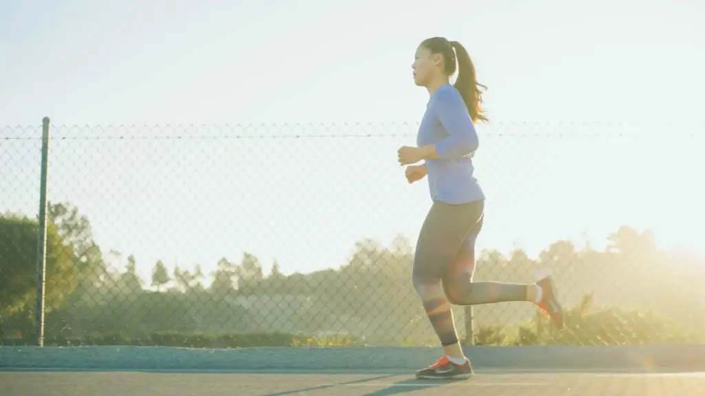 A woman runs through a path on a sunny day