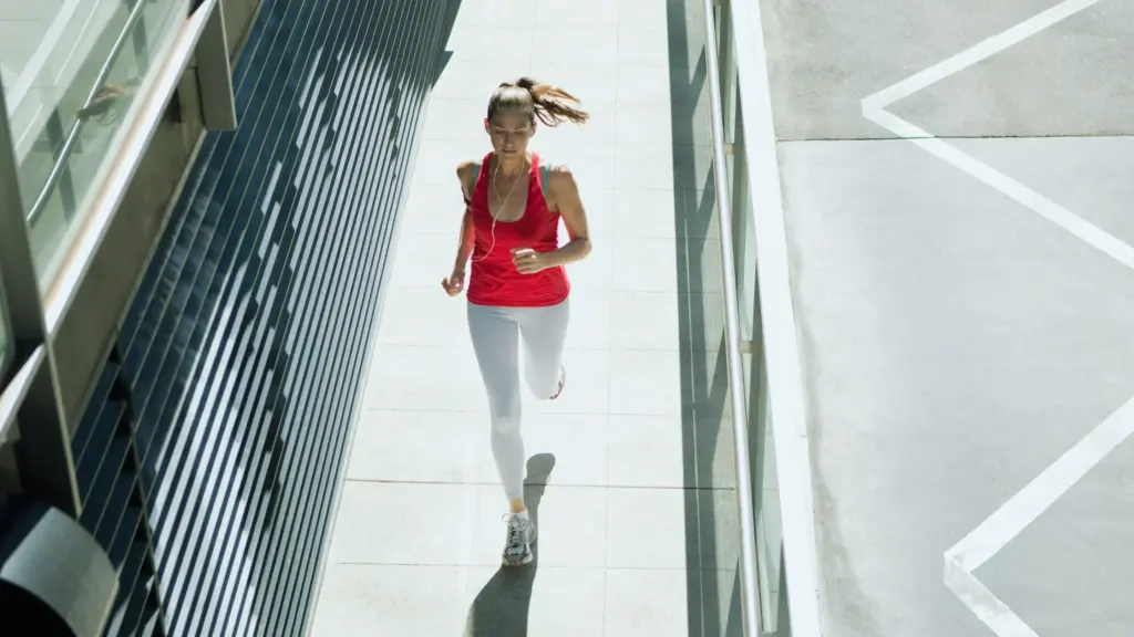 A woman running on a bridge, focused on her workout