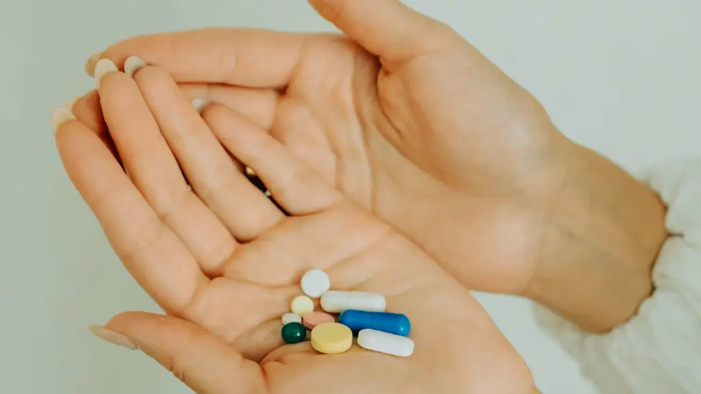 A woman holding various supplement capsules in her palm, showcasing different types of vitamins or nutrients