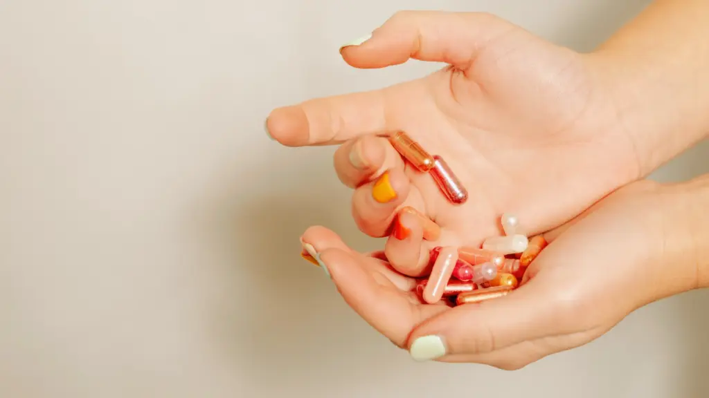 woman holding a pile of different, colorful supplements