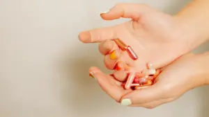 woman holding a pile of different, colorful supplements