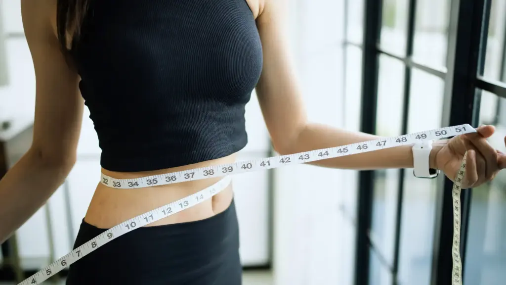 Woman measuring her waist with a measuring tape