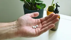 Middle-aged man holding three supplement capsules in his hand