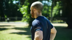 Middle-aged man standing in a field post-workout, catching his breath